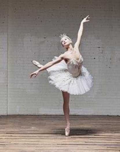 A ballerina stands on her toe and holds out her arms.