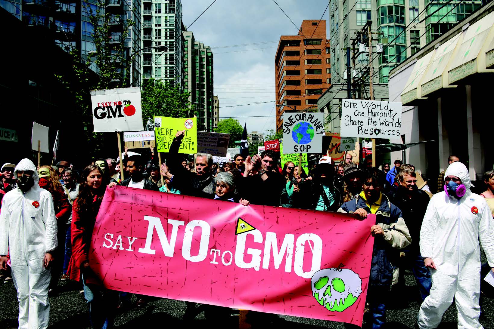 A group of people marching down a street holding signs Description automatically generated with low confidence