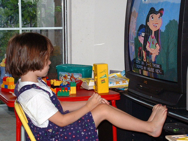 Child watching television with captions.