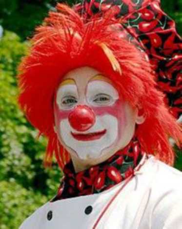 A clown with red hair, white face paint, and a red nose.