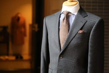 A photograph of an expensive-looking suit jacket with a tie and a shirt on a mannequin. 