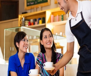 a waiter serving coffee to two women