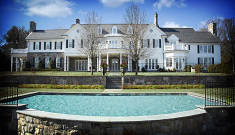 a swimming pool outside a big house