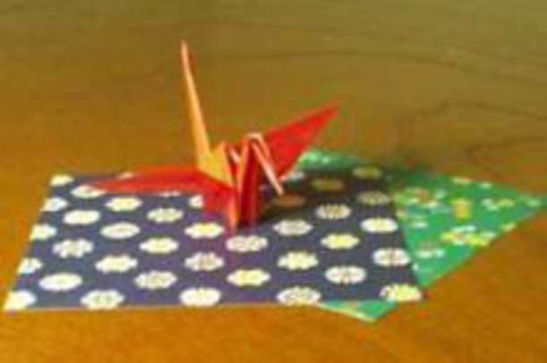 An origami crane placed on decorative origami paper.