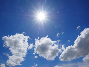 Photograph of the sky on a bright, sunny day with a few white, puffy clouds.