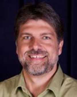 An image of David Brown. He wears a collared shirt and smiles.