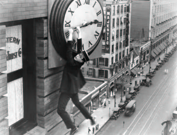 Black and white image of a man hanging from a clock