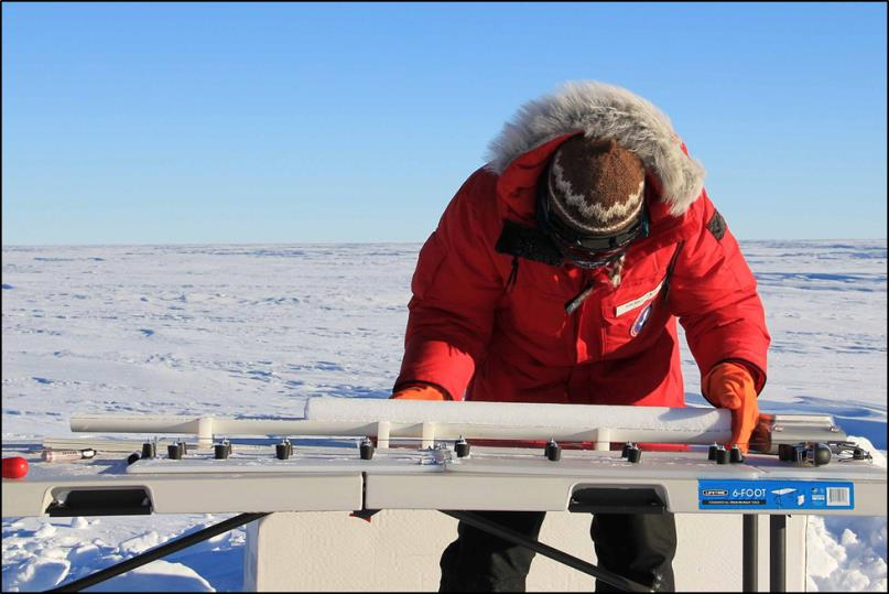photo of man in red parka preparing an ice core