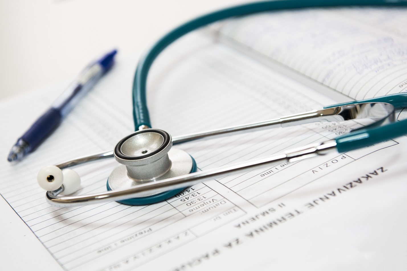 A photograph showing a doctor's report, pen, and stethoscope. 