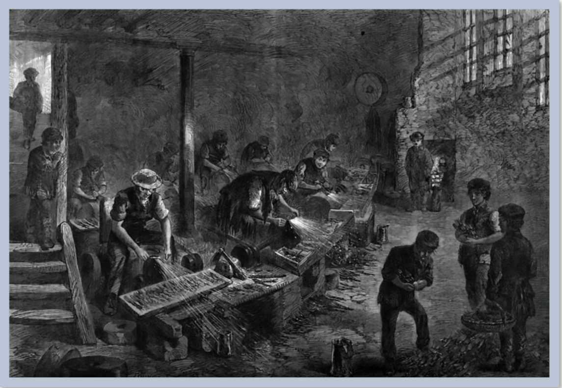 A dark building with several people working at tables welding steel.
