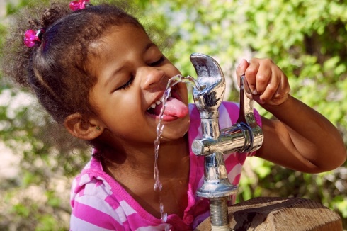a child drinking from a water fountain