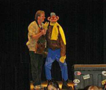 A man on stage holds up a puppet.