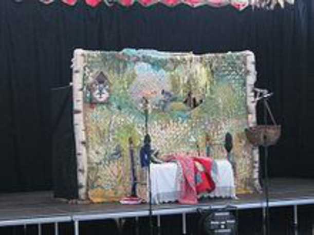 Puppets perform on a stage in front of a set.
