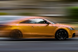 A photograph of a very fast yellow sports car in motion.