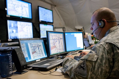 A military service member using computer with multiple monitors.