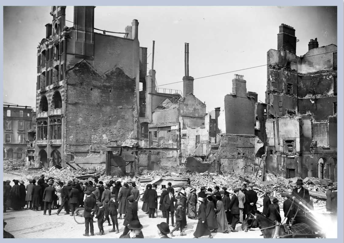 A group of people stand in an old battered town.