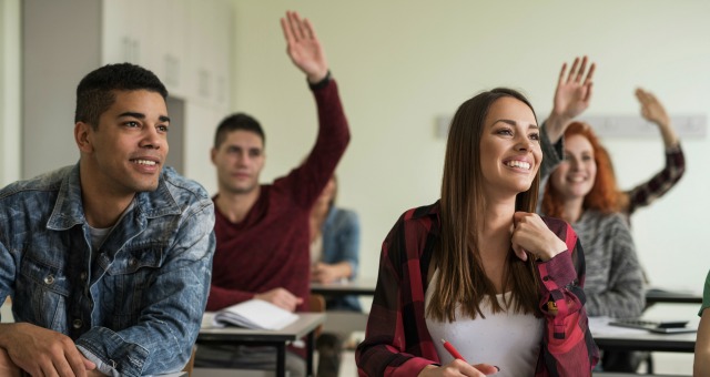 students raise their hands in a classroom