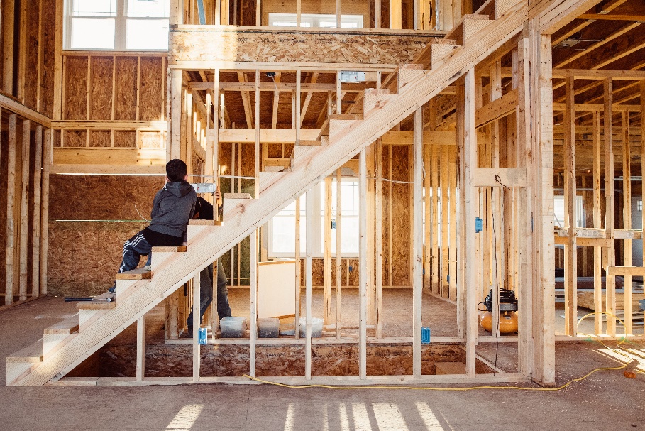 A person sitting on a staircase in an unfinished home.